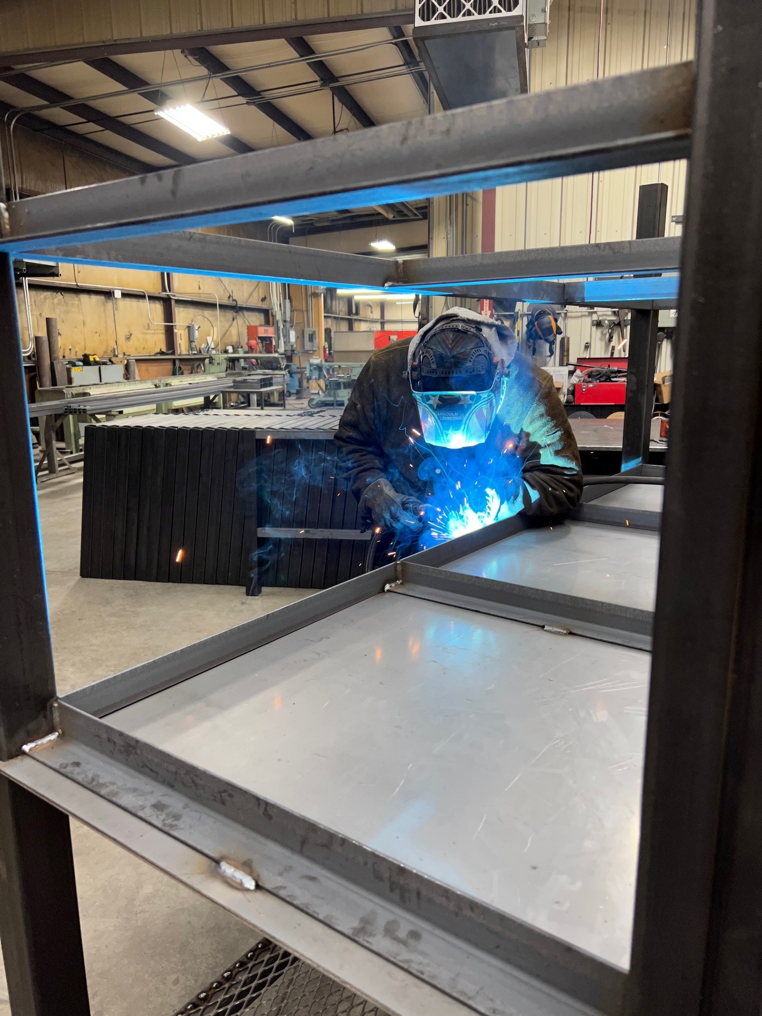 Shop worker welds table frame.